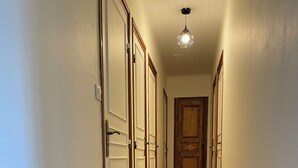 A hallway with white walls, wooden doors, and a tiled floor.