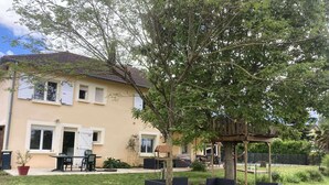 A two-story house with a balcony, outdoor seating, and a tree in the yard.