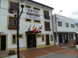 A hotel named "HOTEL E. L. Esmeralda PLAZA" with a white facade, yellow trim, and multiple windows. Flags are displayed outside.