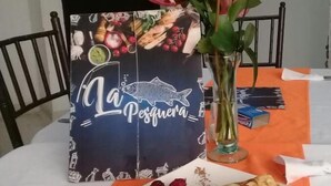 A dining table with a plate of food, a menu, and a vase with flowers. - Hotel Esmeralda Plaza (Zipaquirá)