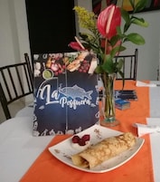 A dining table with a plate of food, a menu, and a vase with flowers.