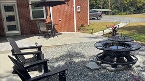 An outdoor patio with Adirondack chairs, a table, and a fire pit. - Quiet 2BR Retreat Near Downtown Albemarle (Albemarle)