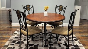 A dining area with a round wooden table, black metal chairs, a patterned rug, and pendant lighting. - Quiet 2BR Retreat Near Downtown Albemarle (Albemarle)