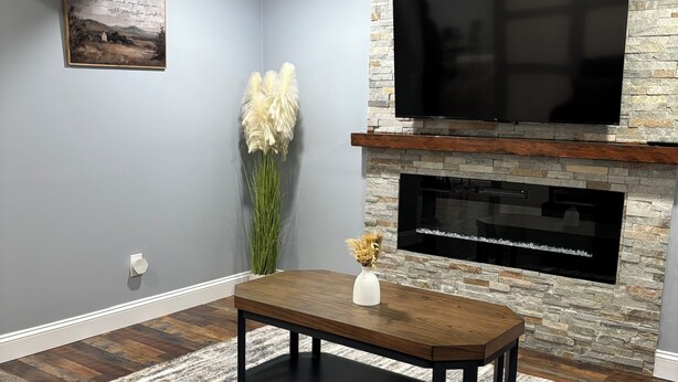 A modern living room with a stone fireplace, a flat-screen TV, and a comfortable seating area. - Quiet 2BR Retreat Near Downtown Albemarle (Albemarle)