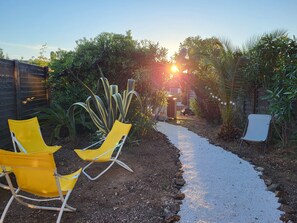 Een tuinpad met gele stoelen en een klein gebouwtje.