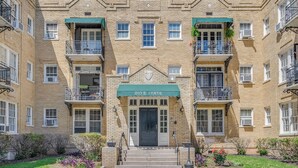 Un immeuble en briques de plusieurs étages, doté d’une entrée centrale, de balcons et d’un auvent vert portant l’inscription « 210 E. STATE ».