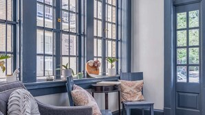 Une pièce confortable avec une grande fenêtre, un canapé, une petite table et une chaise.