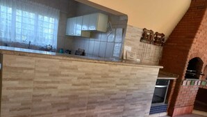 Eine Küche mit gefliestem Rückwand, einem Backofen aus Ziegeln und einem Fenster mit Spitzenvorhängen.