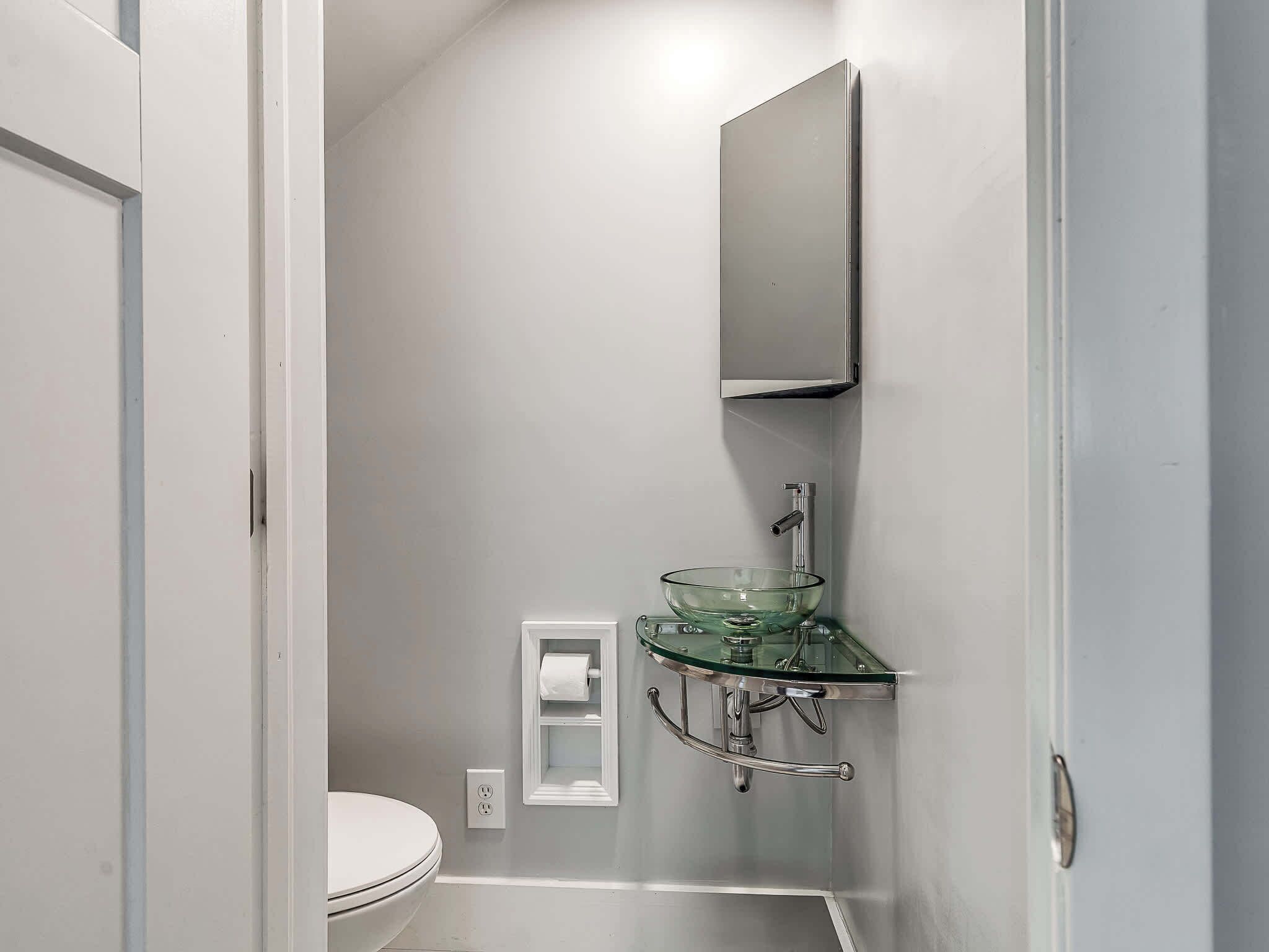 Un bagno piccolo con un lavandino in vetro, un water e uno specchio.