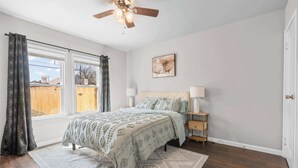 A bedroom with a bed, bedside tables, a ceiling fan, and a window with curtains. - Stylish 1-Bedroom Retreat in Fort Worth (Fort Worth)
