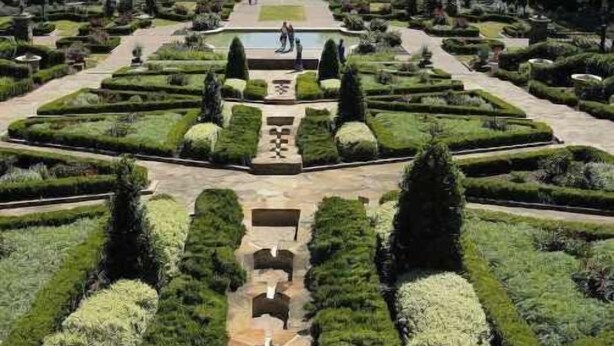 A formal garden with symmetrical pathways, neatly trimmed hedges, and a central water feature. - Stylish 1-Bedroom Retreat in Fort Worth (Fort Worth)