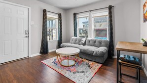 A living room with a grey sofa, a round coffee table, and a wooden side table. - Stylish 1-Bedroom Retreat in Fort Worth (Fort Worth)