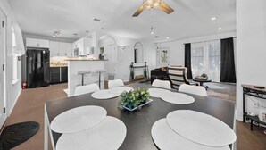 A modern kitchen with white cabinets, a black refrigerator, and a dining area with a large table and white placemats. - Stunning Lake Travis Retreat in Austin (Austin)