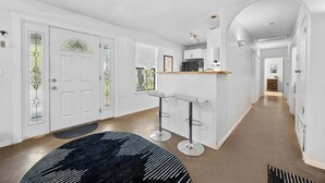A modern kitchen with white cabinetry, a central island with bar stools, and a view to the dining area. - Stunning Lake Travis Retreat in Austin (Austin)