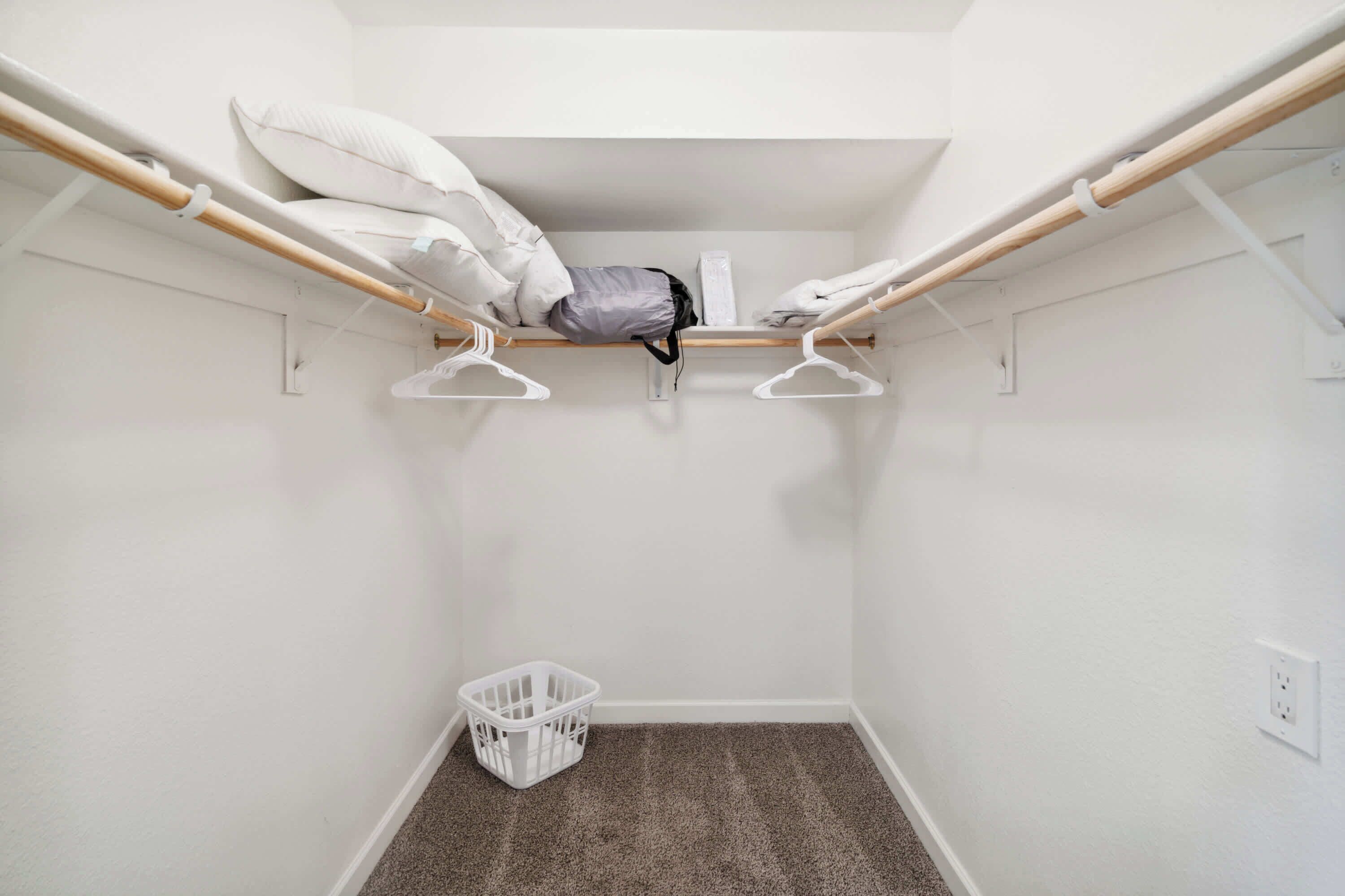 A small, white-walled room with a bunk bed, a white laundry basket, and a white wall socket.