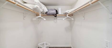 A small, white-walled room with a bunk bed, a white laundry basket, and a white wall socket.