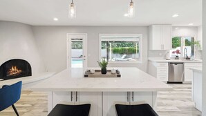 A modern kitchen with a central island, pendant lighting, a fireplace, and a view of the outdoors. - Spacious Scottsdale Retreat with Pool (Tempe)
