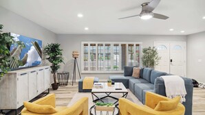 A modern living room with a sofa, yellow chairs, a coffee table, and a ceiling fan. - Spacious Scottsdale Retreat with Pool (Tempe)