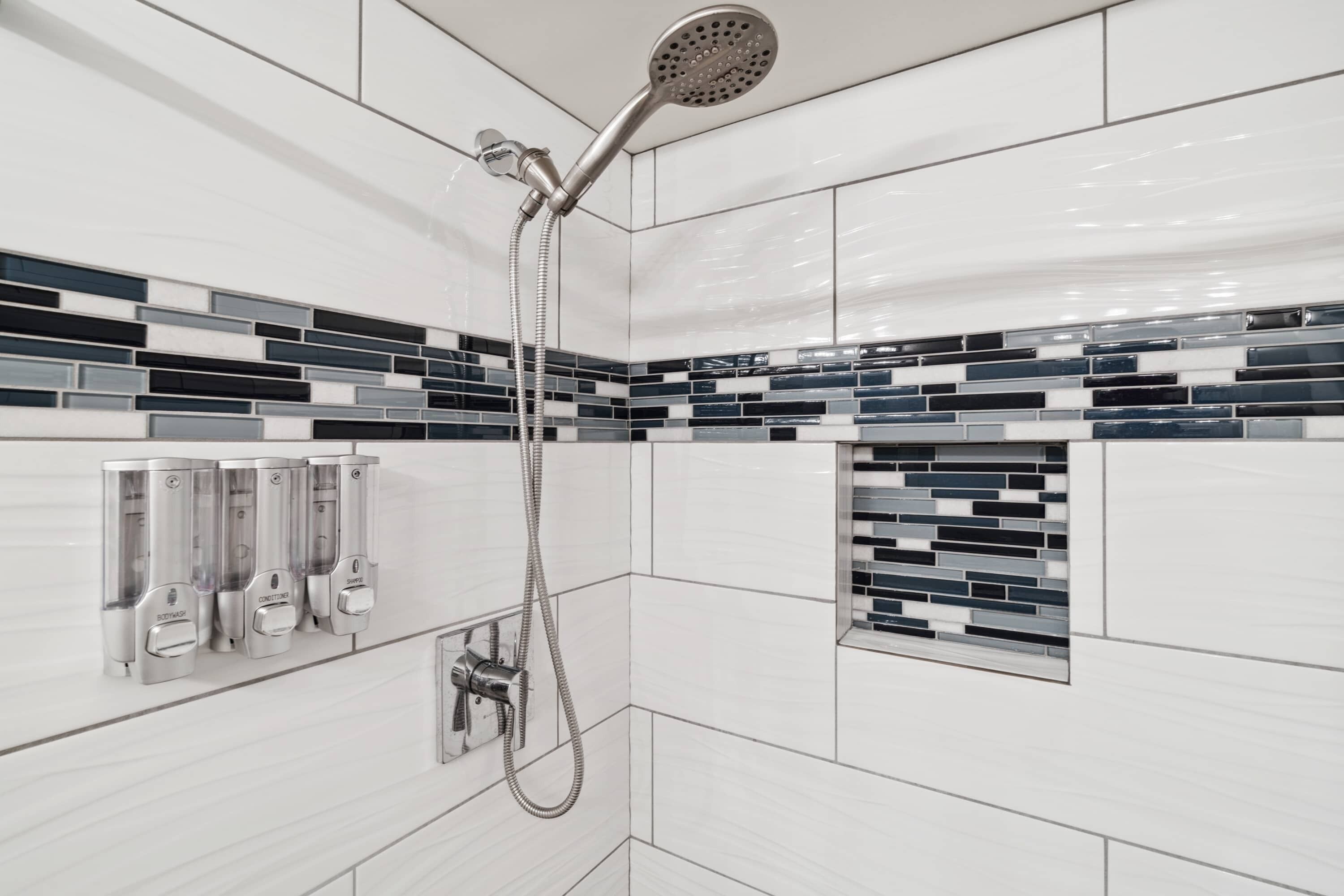 A modern bathroom with a shower, a hand dryer, and a towel dispenser.