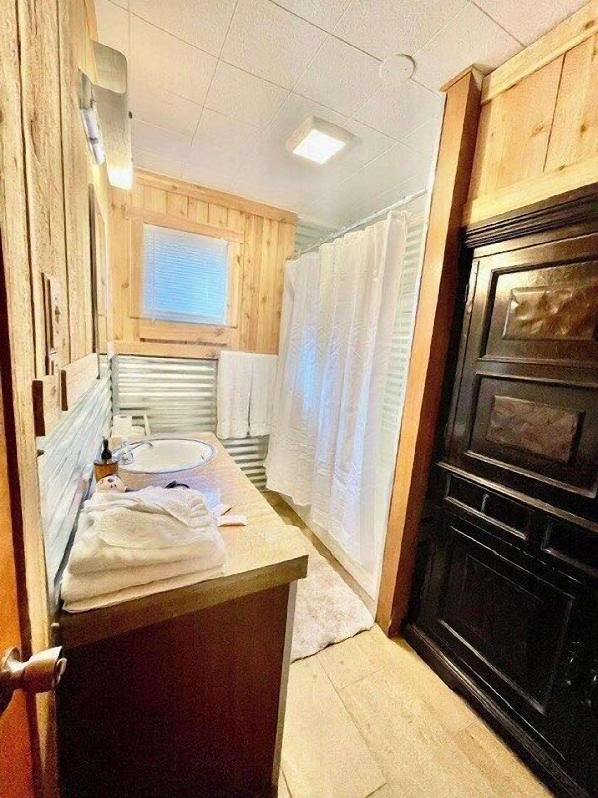 Un baño pequeño con un tocador de madera, un lavamanos y un horno negro.