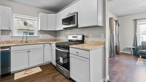A kitchen with white cabinets, a stainless steel microwave, a stove, and an oven. - Charming 1-Bedroom Retreat in Fort Worth (Fort Worth)