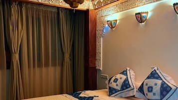 Une pièce comprenant un lit, des rideaux, un plafond décoratif et des lampes fixées au mur.