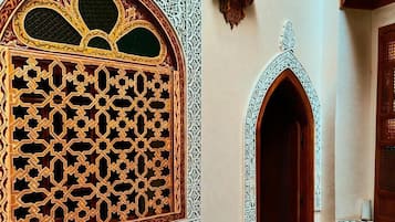 A room with intricate wooden lattice window designs and a small arched doorway.