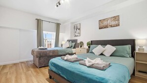 Een moderne slaapkamer met een groot bed, een bank, een nachtkastje en een raam met gordijnen.