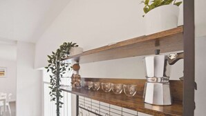 Een keuken met een houten plank, een koffiezetapparaat en hangende mokken.