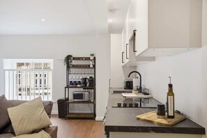 A modern kitchen with a microwave, kettle, and a bottle of olive oil on the counter.