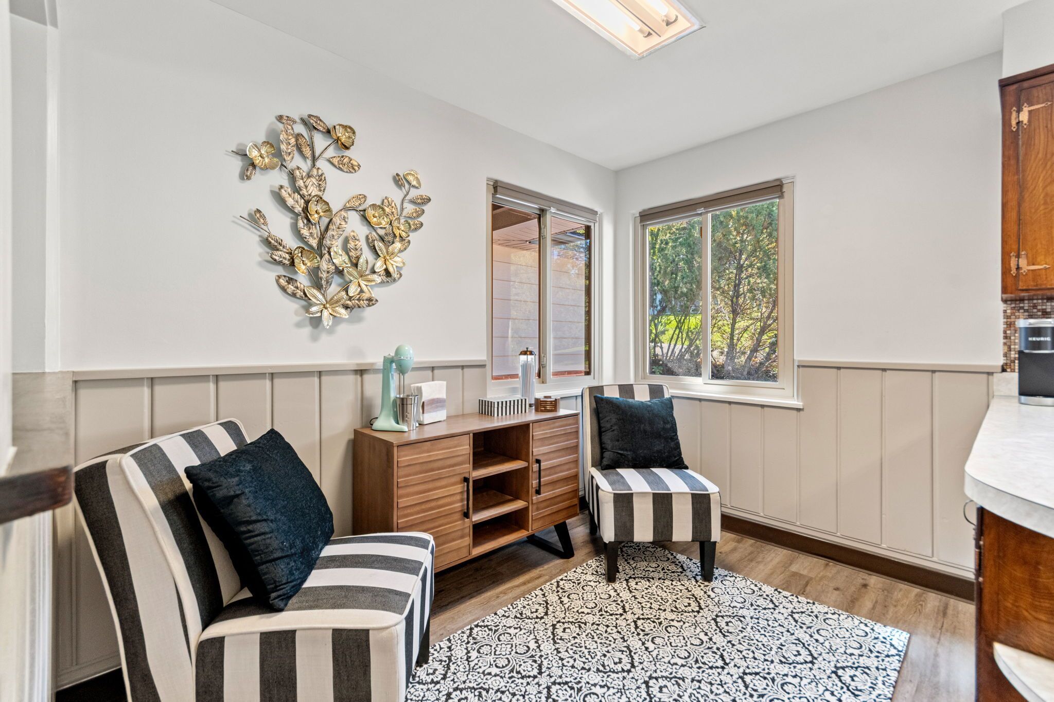 A modern living room with striped sofas, a patterned rug, and a decorative wall piece.