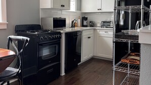 Una cocina moderna con armarios blancos, una estufa negra, un lavavajillas, un microondas y un horno empotrado.
