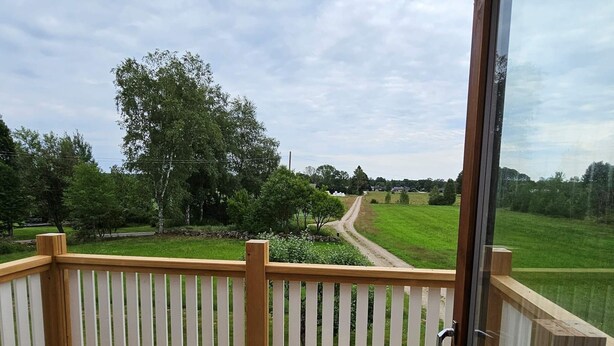 A wooden deck with a white railing, overlooking a grassy field and trees. - 8 Person Holiday Home in Ryssby (Ryssby)