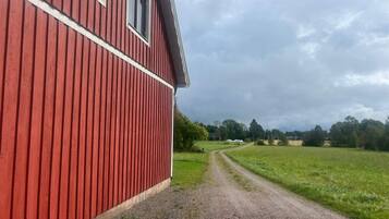 Un edificio rojo con camino de grava que lleva a un paisaje rural.