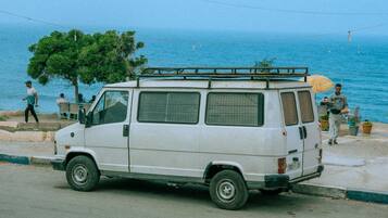 Un fourgon blanc est garé au bord de la route, avec la mer en toile de fond.