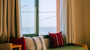 Quarto com janela, um banco de madeira e duas almofadas.