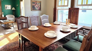 A dining area with a wooden table set for four, surrounded by wicker chairs. - Brunswick 3BR Bungalow By Bowdoin With Fenced-In Backyard (Brunswick)