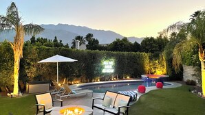 Un giardino sul retro con piscina, area salotto esterna e un braciere.