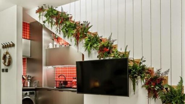 Una cucina moderna con lavatrice integrata, un'area pranzo con tavolo in legno e una TV fissata a parete.