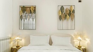 Una camera da letto con un letto, due comodini e due elementi decorativi a forma di foglia applicati alla parete.