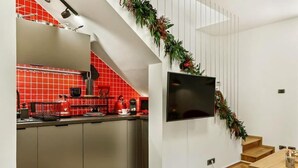 Una cucina moderna con piastrelle rosse, forno integrato e televisore a schermo piatto fissato al muro.
