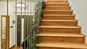 Una scala con gradini in legno che sale, delimitata da una ringhiera metallica e piante.