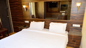 A hotel room with a large bed, wooden paneling on the walls, a mirror above the bed, and two wall-mounted light fixtures. - BAGA RESIDENCY (Calangute)