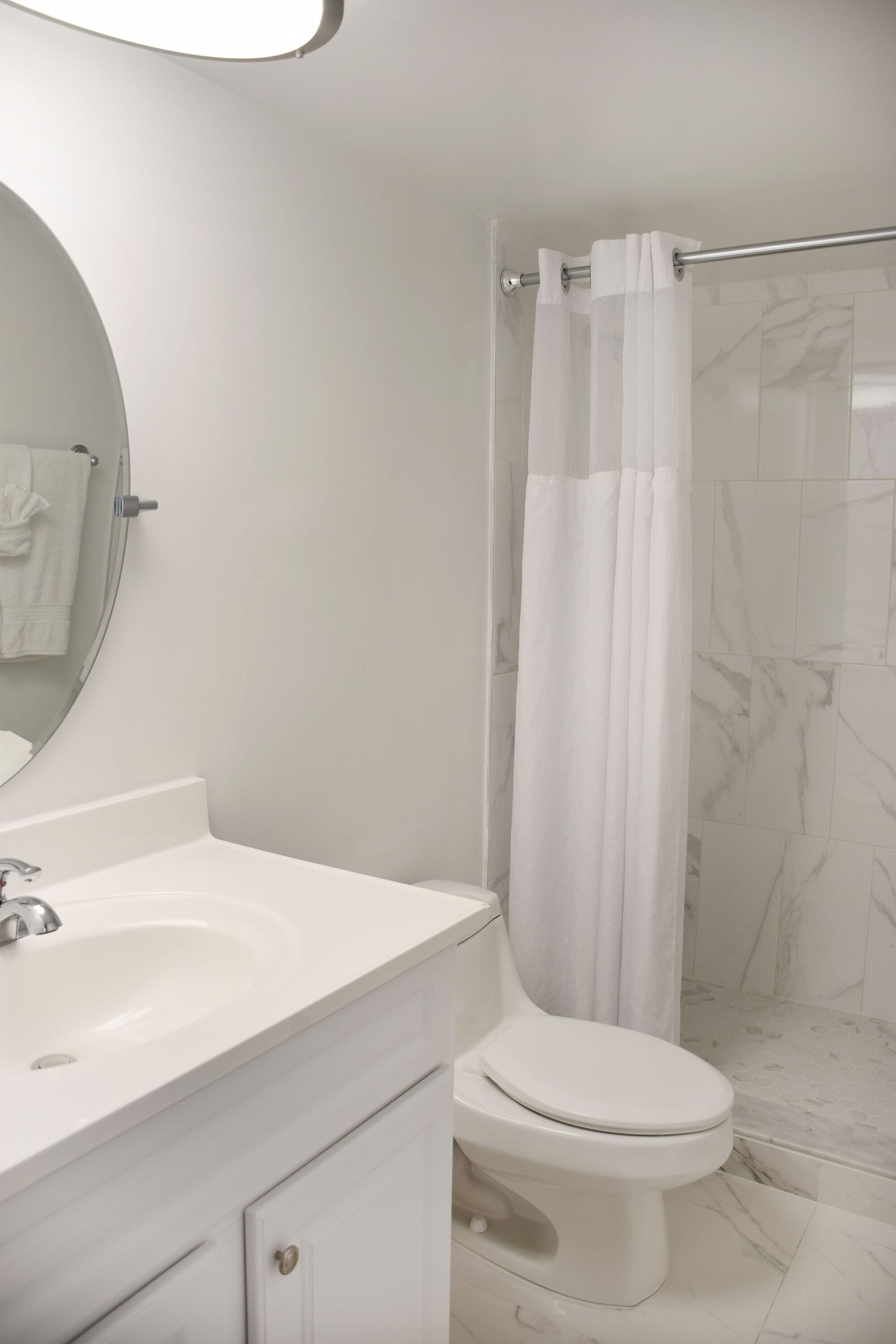 A bathroom with a white sink, toilet, and shower curtain.
