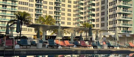A high-rise hotel with a swimming pool, multiple balconies, and outdoor seating areas.