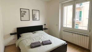 A bedroom with a bed, two wall art pieces, a window, and a radiator. - Casa Sforza - stylish apartment in the heart of Bergamo! (Bergamo)