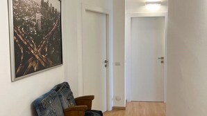 A hallway with a wooden floor, a brown sofa with denim cushions, and a framed cityscape picture on the wall. - Casa Sforza - stylish apartment in the heart of Bergamo! (Bergamo)