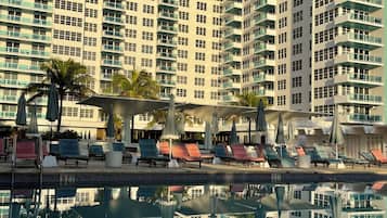 A high-rise hotel with a swimming pool, multiple balconies, and outdoor seating areas.