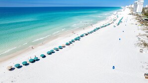 Ein Strand mit Reihen von Sonnenschirmen und einem Gebäude im Hintergrund.