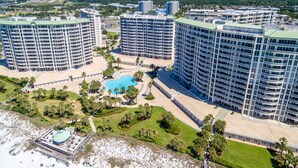 Ein Hochhotel mit mehreren Balkonen, einem zentral gelegenen Schwimmbecken und einer Strandanlage.